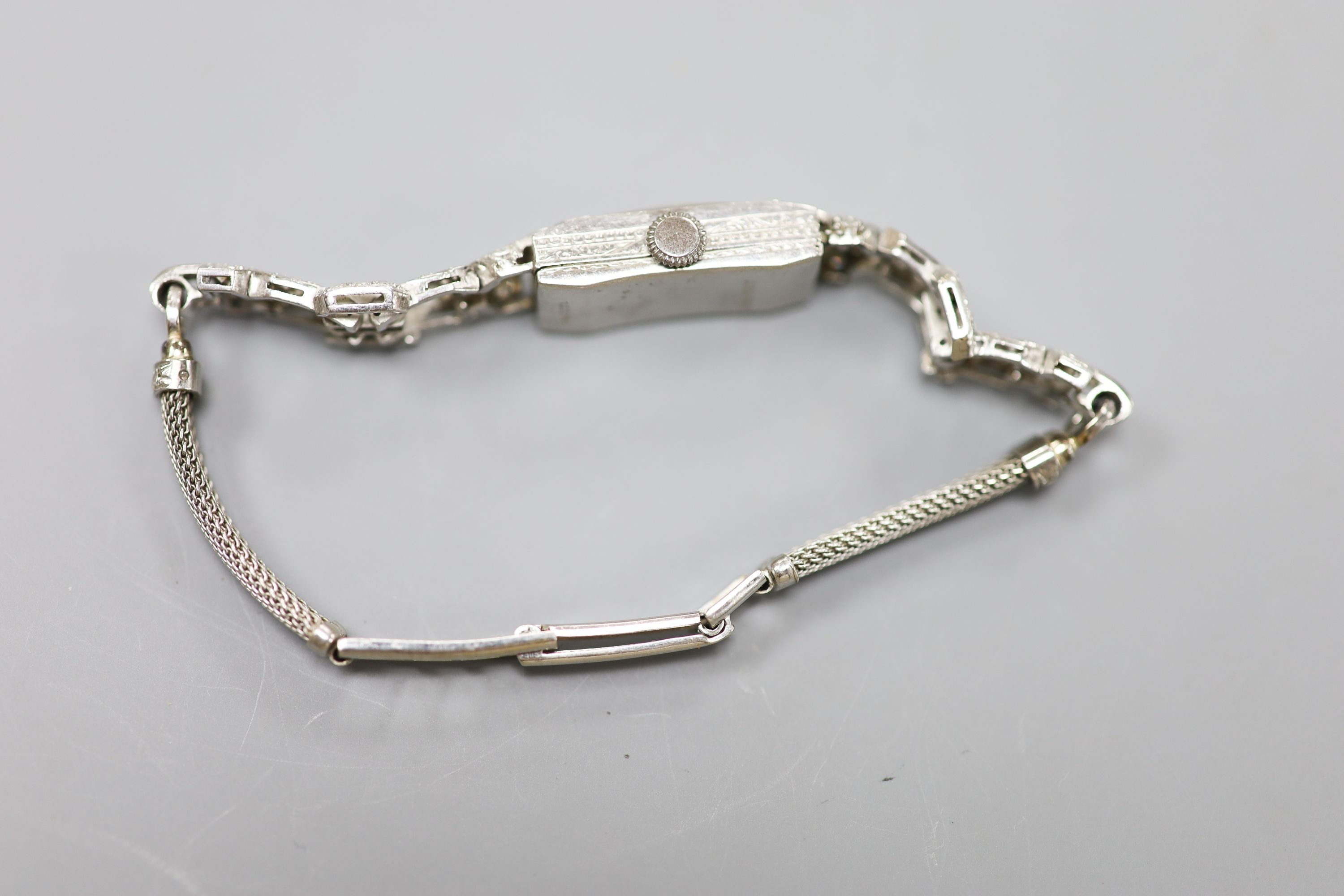 A white metal (stamped All platinum) and diamond set manual wind cocktail watch, on a 9ct white metal mesh bracelet, gross weight 21.6 grams.